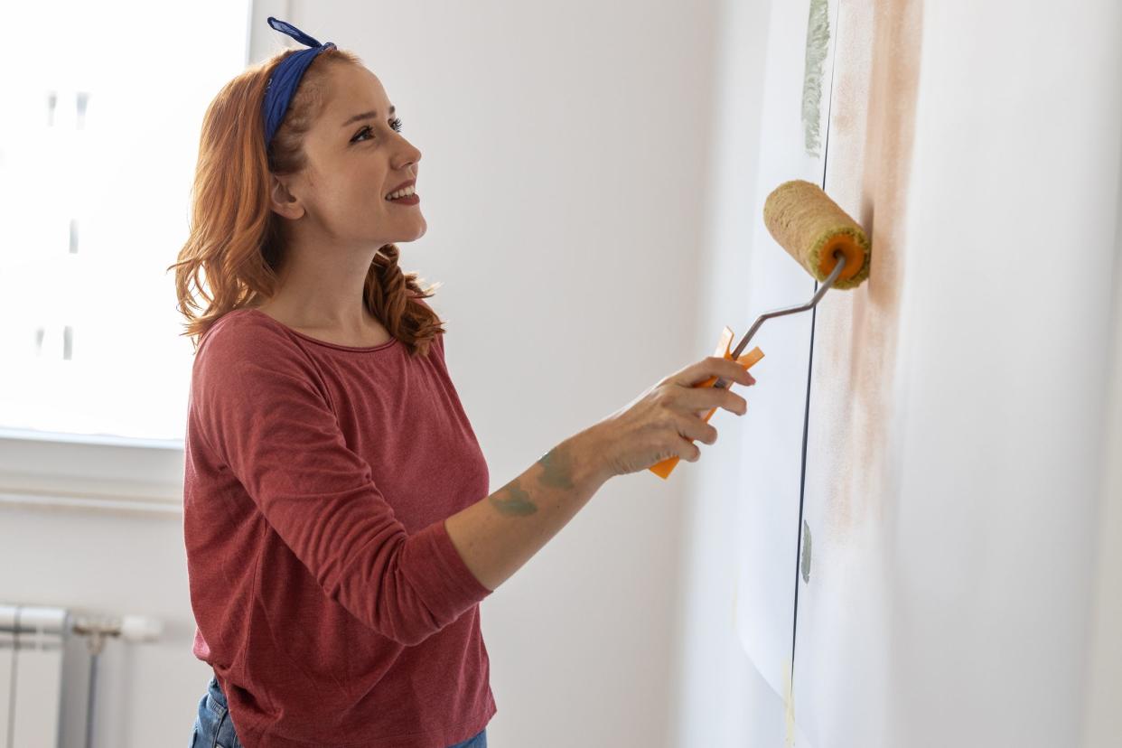 Young woman using paint roller to decorate walls