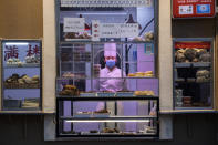 In this photo taken Saturday, Feb. 22, 2020, a chef looks out from behind a display of food products at a restaurant in Beijing, China. Regulators on Monday promised tax cuts and other aid to help companies recover from China's virus outbreak and expressed confidence the ruling Communist Party's growth targets can be achieved despite anti-disease controls that shut down much of the economy. (AP Photo/Ng Han Guan)