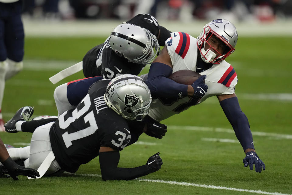 New England Patriots tight end Jonnu Smith is taken down by Las Vegas Raiders cornerback Tyler Hall and cornerback Nate Hobbs after a pass reception during the first half of an NFL football game between the New England Patriots and Las Vegas Raiders, Sunday, Dec. 18, 2022, in Las Vegas. (AP Photo/John Locher)