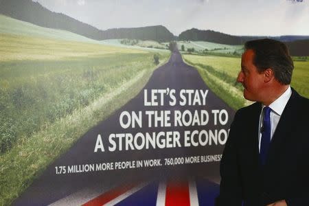 Britain's Prime Minister David Cameron looks at a new Conservative Party poster after unveiling it at Dean Clough Mill in Halifax, northern England January 2, 2015. REUTERS/Phil Noble