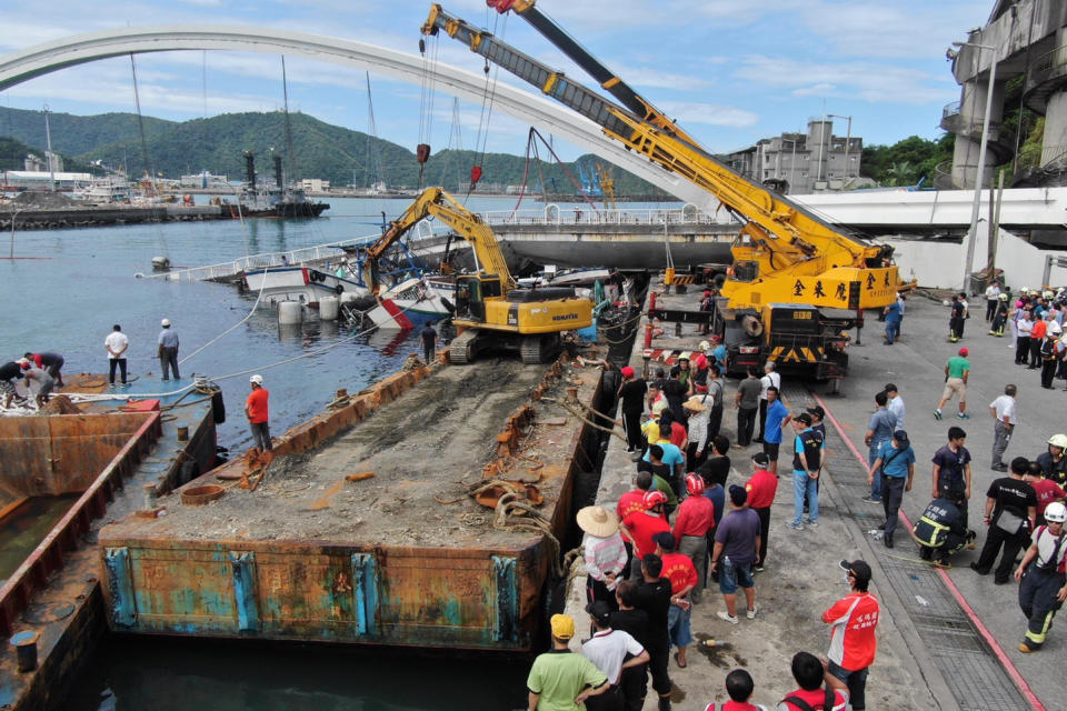 People watch a collapsed bridge in Nanfangao, eastern Taiwan. Tuesday, Oct. 1, 2019. A towering bridge over a bay in eastern Taiwan has collapsed sending an oil tanker truck falling onto boats in the water below.(Taiwan's National Fire Agency via AP)