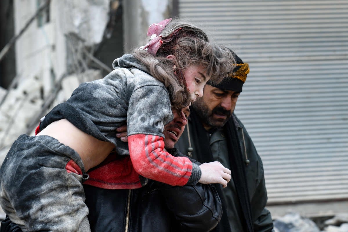 Residents carry an injured child from the rubble of a collapsed building following an earthquake in the town of Jandaris, in the countryside of Syria’s northwestern city of Afrin in the rebel-held part of Aleppo province (AFP via Getty Images)