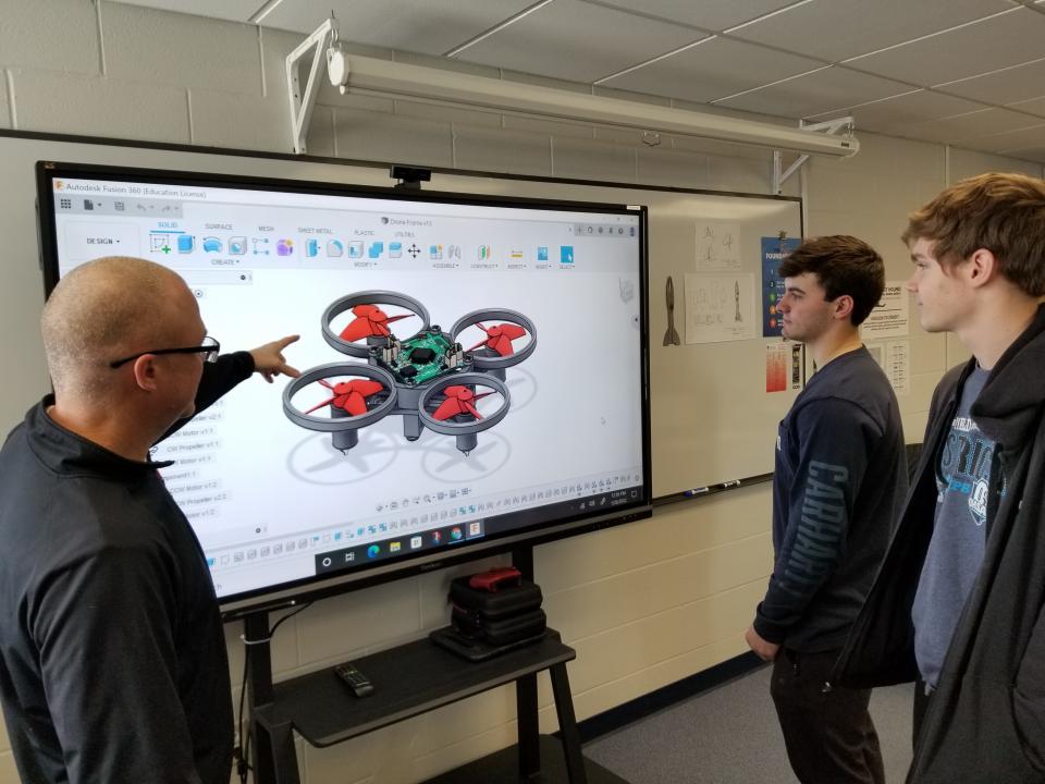 Andrew Toye (far left) talks to two of his students, Nolan Yoder and Micah Kuhns, about drones. Toye is a teacher at Hiland High and Middle School and with the grant money his school was awarded recently, he hopes to buy drone kits.