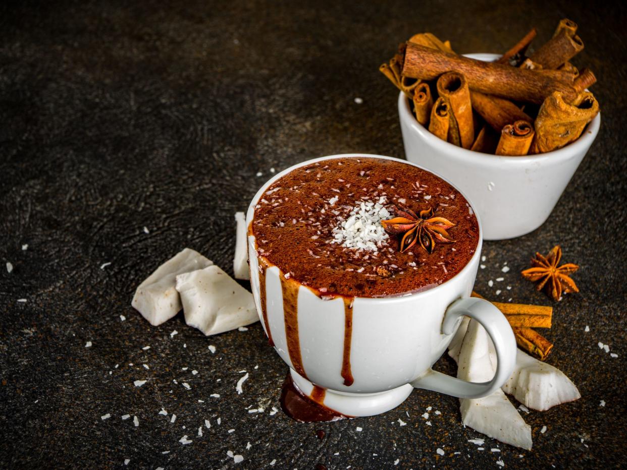 Vegan coconut hot chocolate, with coconut slices, dark background copy space