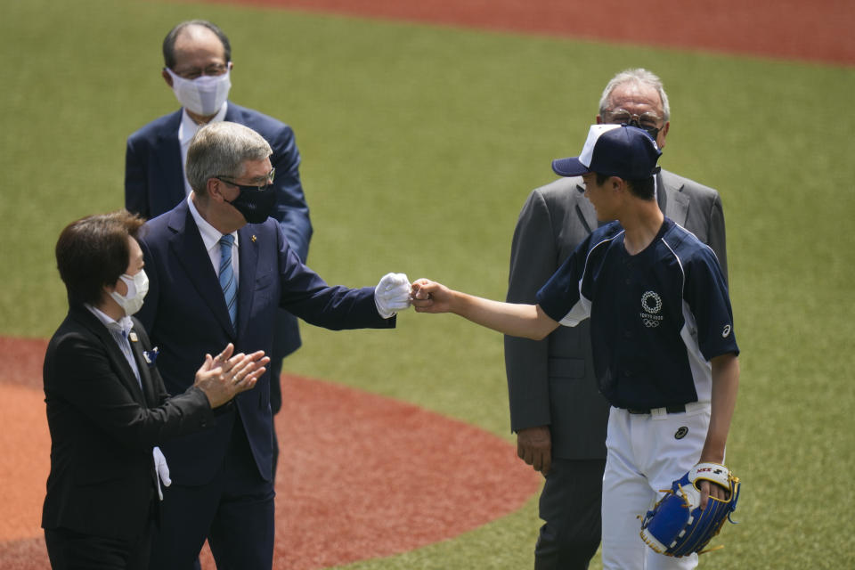 International Olympic Committee President Thomas Bach, left, fist bumps Yuma Takara, 14, after Takara threw the ceremonial first pitch before a baseball game between Japan and the Dominican Republic at the 2020 Summer Olympics, Wednesday, July 28, 2021, in Fukushima, Japan. (AP Photo/Jae C. Hong)