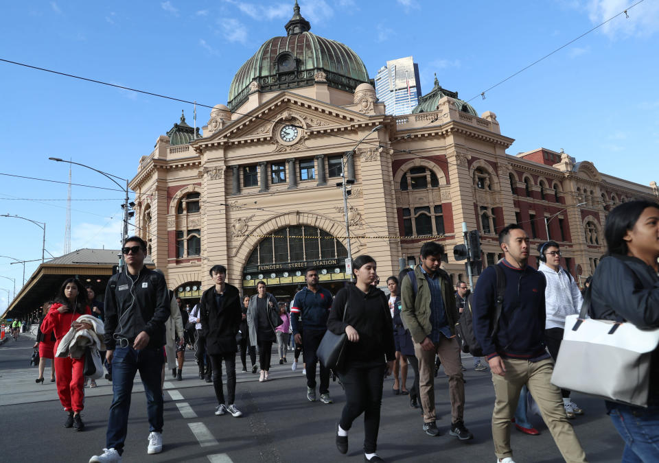 Pedestrians cross the intersection in front of Flinders Street Station in Melbourne.