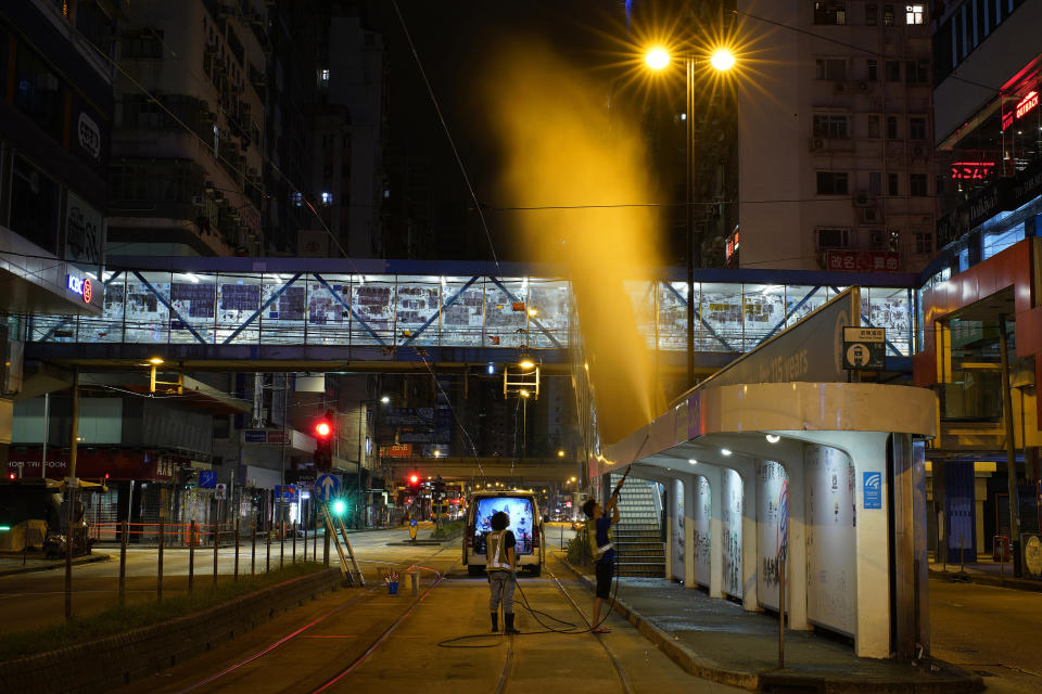 In this Sept. 18, 2019, photo, a cleaner attempts to erase anti-government graffiti by using a high-presser water gun in Hong Kong. Cleaners in Hong Kong have been working around the clock to erase remnants of weekly battles. As Hong Kong enters its fourth month of steady protests, the city is embracing for another violent weekend prior to the upcoming 70th National Day on Oct. 1. (AP Photo/ Vincent Yu)