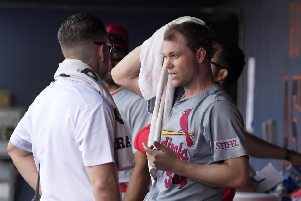 St. Louis Cardinals starting pitcher Sonny Gray, right, talks in the dugout with trainer Adam Olsen after being removed during the second inning of a spring training baseball game against the Washington Nationals Monday, March 4, 2024, in West Palm Beach, Fla. The team announced that Gray was removed due to tightness in his right hamstring. (AP Photo/Jeff Roberson)