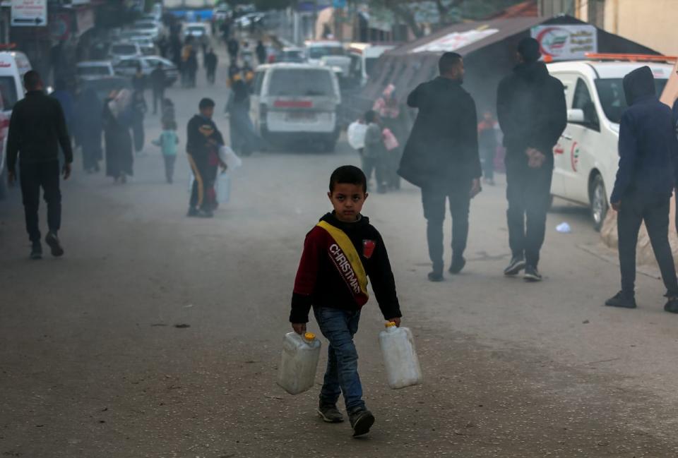A Palestinian child displaced by the Israeli ground offensive on the Gaza Strip carries jerry cans at a makeshift tent camp in Rafah, Gaza Strip, Monday, Feb. 19, 2024.