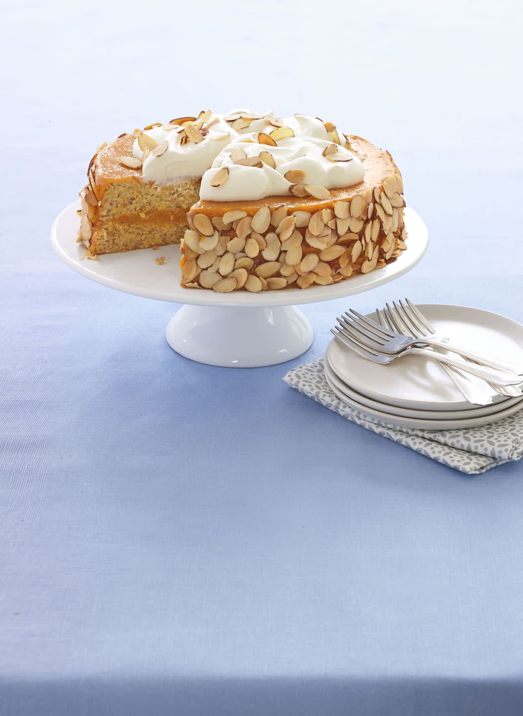 almond apricot cake with cream on top, served on a cake stand