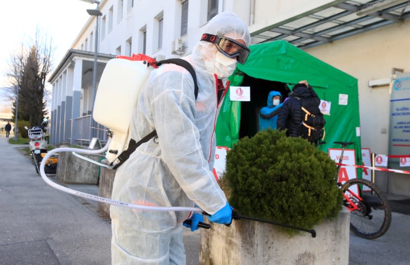 FILE PHOTO: A worker sprays disinfectant to prevent the spread of coronavirus disease (COVID-19), outside the hospital in Kranj