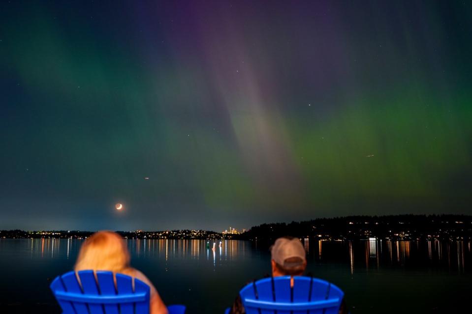 Stargazers view the northern lights, or aurora borealis, as they glow over Lake Washington, in Renton, Washington. AP