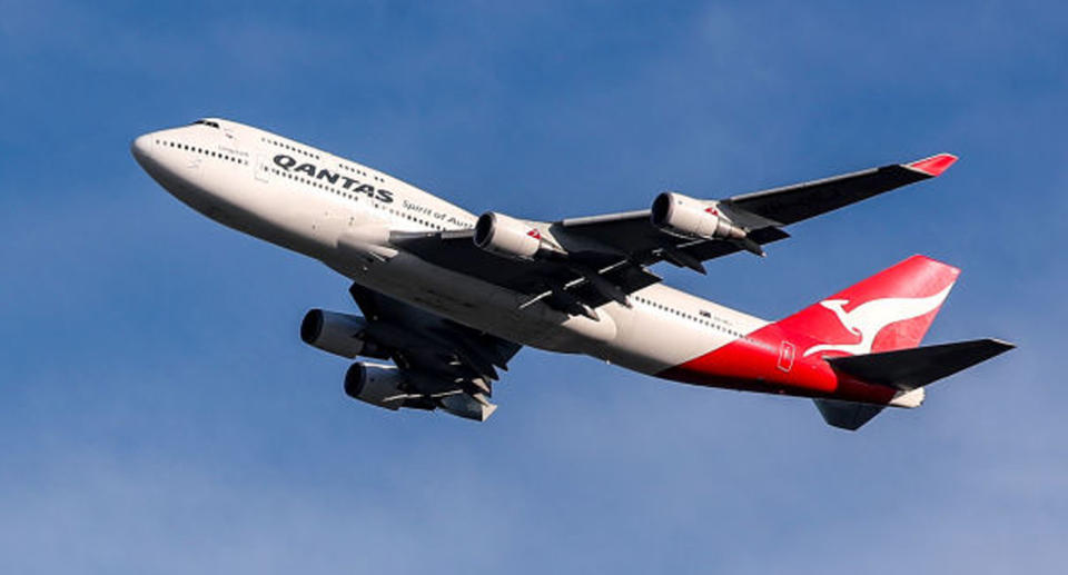 A Qantas plane takes off on a sunny day.