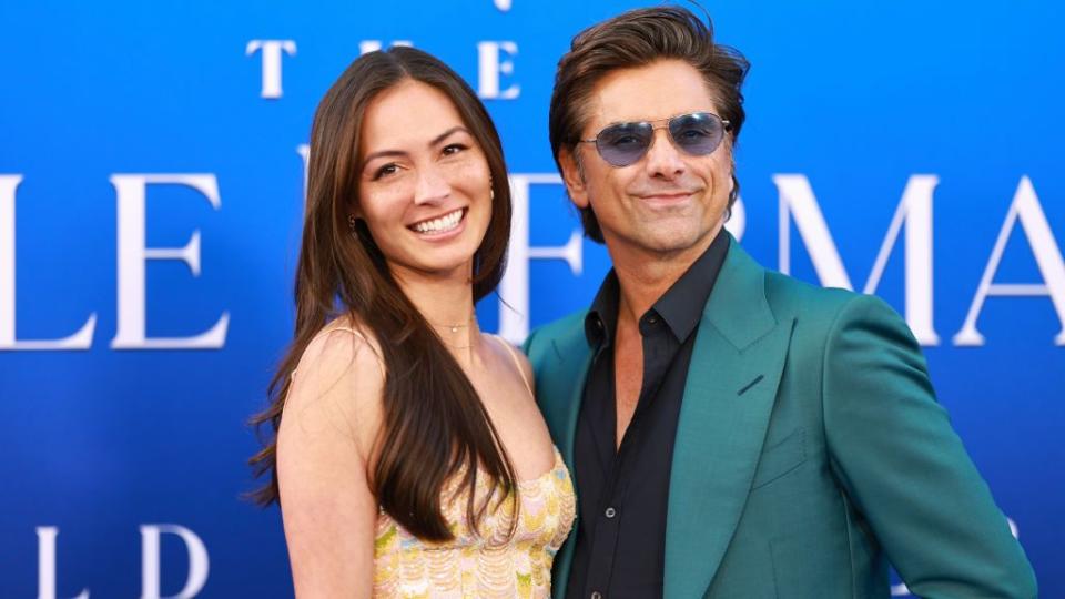 john stamos embracing wife caitlin mchugh for a photo at a film premiere