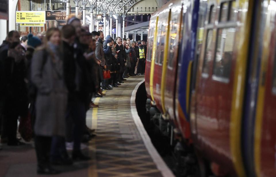 Commuters wait for trains at Clapham Junction train station (AP)