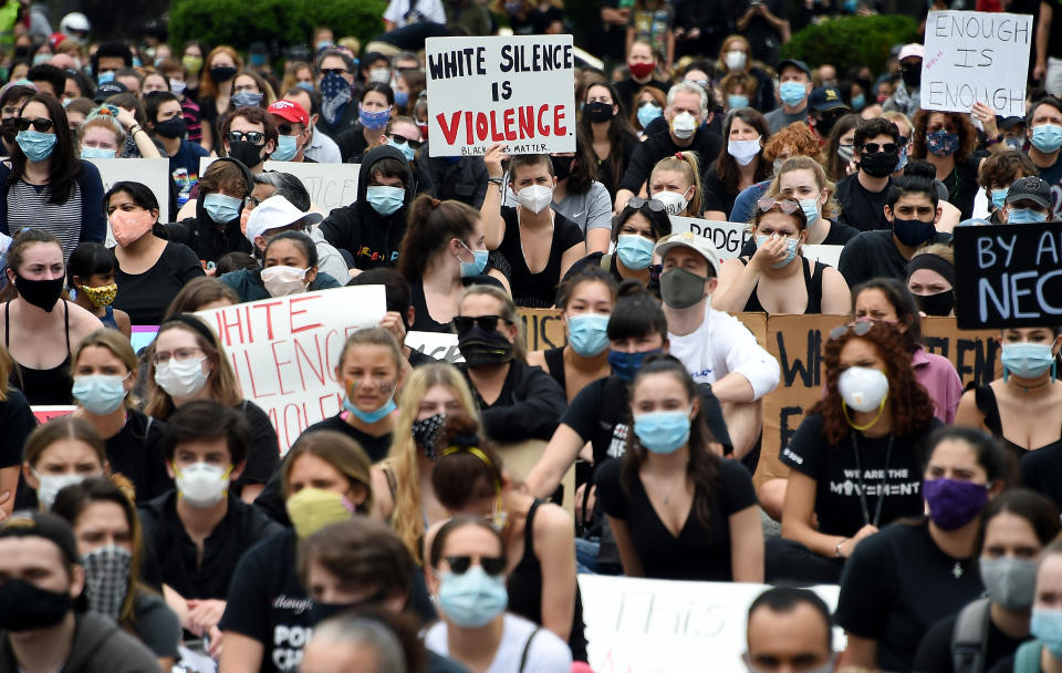 Peaceful demonstrators hold signs as they protest the death of George Floyd hold up placards outside the Bethesda Library on June 2, 2020 in Bethesda, Maryland. - Anti-racism protests have put several US cities under curfew to suppress rioting, following the death of George Floyd while in police custody. (Photo by Olivier DOULIERY / AFP) (Photo by OLIVIER DOULIERY/AFP via Getty Images)