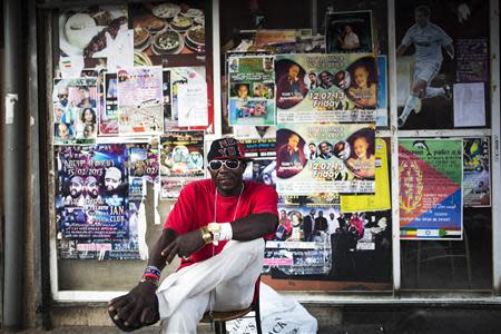 An African migrant sits on a street corner in south Tel Aviv July 17, 2013. REUTERS/Amir Cohen