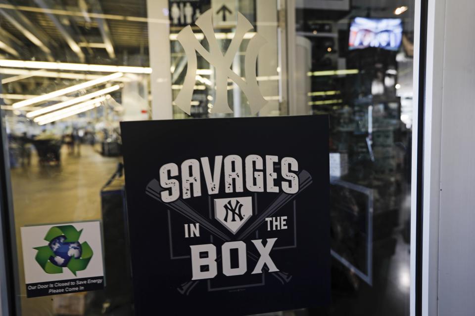 Employees pass signage for the "Savages in the Box" at the New York Yankees team Store before the second game of a baseball doubleheader against the Baltimore Orioles, Monday, Aug. 12, 2019, in New York. (AP Photo/Frank Franklin II)