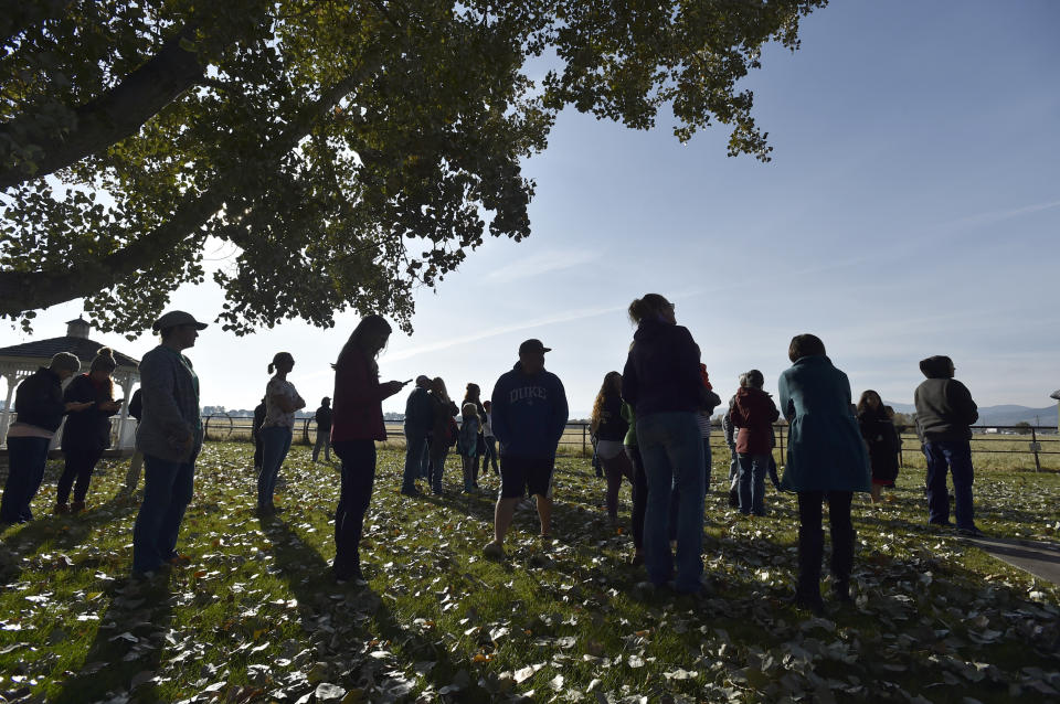 CORRECTS TO SAY WHAT AUTHORITIES THOUGHT WERE THE REMNANTS OF AN EXPLOSIVE DEVICE TURNED OUT TO BE A NONEXPLOSIVE DEVICE - Parents wait for their evacuated students in Helena, Mont., Tuesday, Oct. 15, 2019, after authorities found what they thought were the remnants of an improvised explosive device at the playground of the Rossiter Elementary School. Authorities evacuated the elementary school in Montana's capital city Tuesday after officials found the unknown materials, but they turned out to be a plastic bottle filled with nuts and bolts left in the schoolyard. (Thom Bridge/Independent Record via AP)