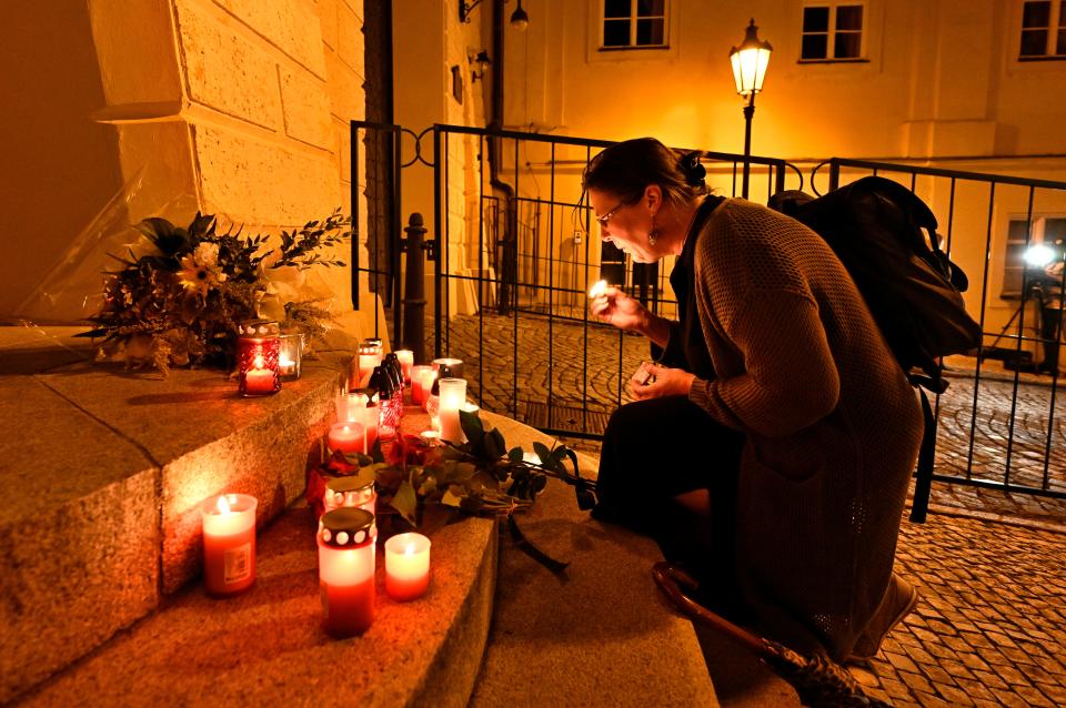 A woman lights a candle in front of the British Embassy in Prague to express grief over Queen Elizabeth's death.