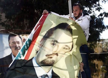 Men take down a picture of former Lebanese Prime Minister Saad al-Hariri in the mainly Sunni Beirut neighbourhood of Tariq al-Jadideh February 5, 2015. REUTERS/Mohamed Azakir