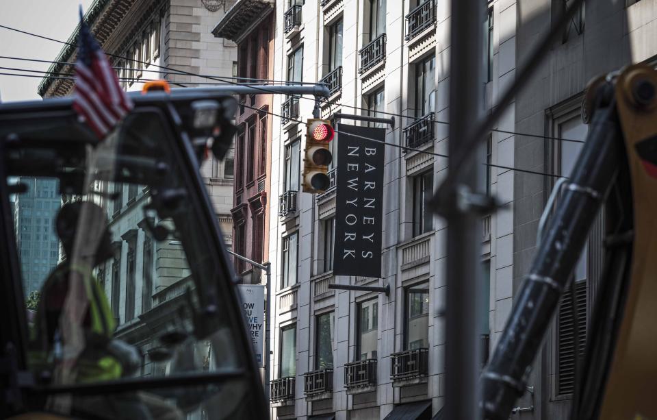 FILE - In this July 16, 2019, file photo a crane operator works equipment on a roadway near Barneys department store in New York. Barneys New York, which opened its 10-story Madison Avenue store in 1993, became a cultural icon in luxury shopping but now risks closure. High rents and a dramatic shift toward online shopping are pressuring it to evaluate restructuring options, including possible bankruptcy, according to a source close to the matter who asked to remain anonymous because the discussions are confidential. (AP Photo/Bebeto Matthews, File)