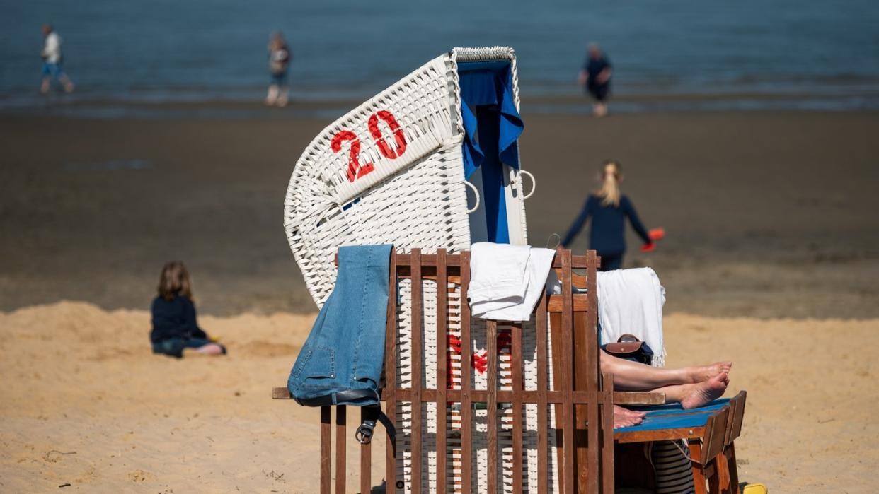Strandbesucher liegen in Cuxhaven in der Sonne. Foto: Mohssen Assanimoghaddam