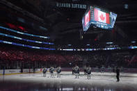 Seattle Kraken and Vancouver Canucks players stand during the Canadian national anthem before an NHL hockey game Saturday, Oct. 23, 2021, in Seattle. (AP Photo/Ted S. Warren)