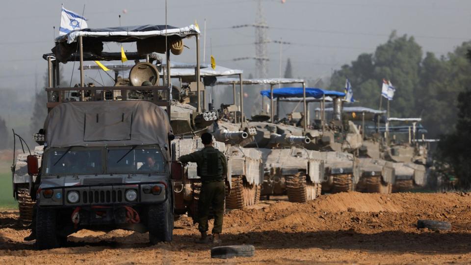 PHOTO: An Israeli soldier stands next to a military vehicle and a convoy of tanks near Israel's border with Gaza, amid the ongoing conflict between Israel and the Palestinian Islamist group Hamas, in Israel, Dec. 4, 2023.  (Amir Cohen/Reuters)