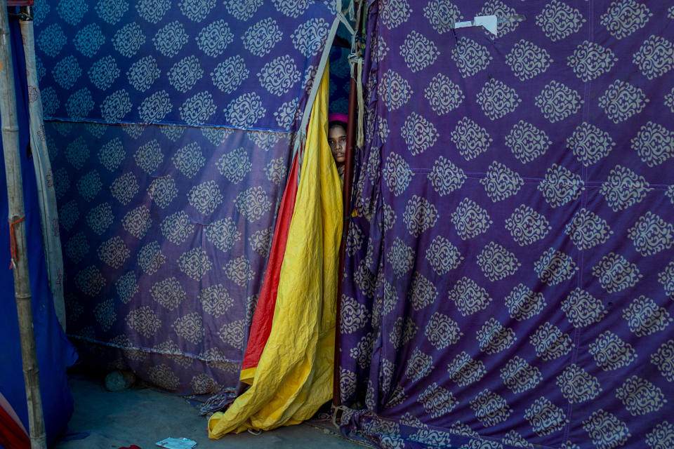 A Rohingya refugee woman peeps out from her tent at a refugee camp alongside the banks of the Yamuna River in the southeastern borders of New Delhi, sprawling Indian capital, July 1, 2021. Millions of refugees living in crowded camps are waiting for their COVID-19 vaccines. For months, the World Health Organization urged countries to prioritize immunizing refugees, placing them in the second priority group for at-risk people, alongside those with serious health conditions. (AP Photo/Altaf Qadri)