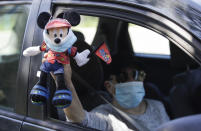 FILE - In this June 27, 2020, file photo, a Disney employee carries a Mickey Mouse doll during a drive-by protest to demand a safe reopening amid the coronavirus pandemic in Anaheim, Calif. President Donald Trump weighed in on Wednesday, July 8, 2020, threatening to withhold federal money from school districts if they don't open their doors for the new school year in the fall. California Gov. Gavin Newsom dismissed that threat. Newsom has ordered people to wear face coverings in public places both indoors and outdoors. The state is closely monitoring new cases, placing counties on a watch list if their numbers are too high. Any county on the list for three consecutive days must shutter bars and close indoor operations at restaurants, movie theaters, wineries, zoos, museums, card rooms, and family entertainment centers like bowling alleys, miniature golf, and arcades. (AP Photo/Marcio Jose Sanchez, File)