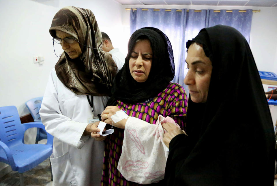 An Iraqi patient, center, leaves after casting her vote at a polling center inside al-Kindi hospital in Baghdad, Iraq, Monday, April 28, 2014. Amid tight security, some one million Iraqi army and police personnel have started voting for the nation's new parliament. (AP Photo/ Karim Kadim)