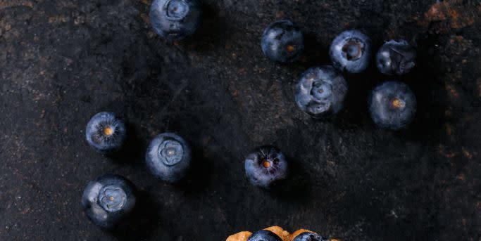 lemon tartlet with fresh blueberries over black background top view with space for text