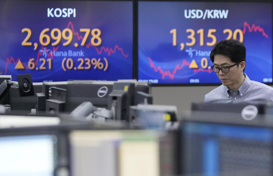 A currency trader passes by the screens showing the Korea Composite Stock Price Index (KOSPI), left, and the foreign exchange rate between U.S. dollar and South Korean won at the foreign exchange dealing room of the KEB Hana Bank headquarters in Seoul, South Korea, Thursday, March 14, 2024. Asian shares mostly declined Thursday in lackluster trading after U.S. stocks drifted to a mixed finish.(AP Photo/Ahn Young-joon)