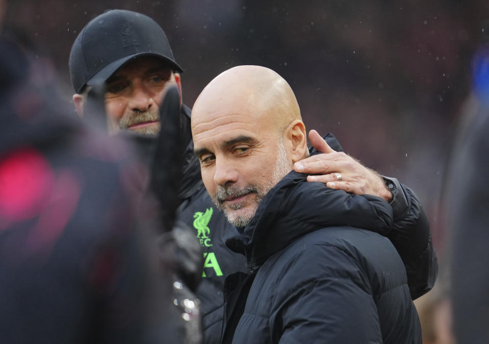 Liverpool's manager Jurgen Klopp, background, hugs Manchester City's head coach Pep Guardiola head of the English Premier League soccer match between Liverpool and Manchester City, at Anfield stadium in Liverpool, England, Sunday, March 10, 2024. (AP Photo/Jon Super)