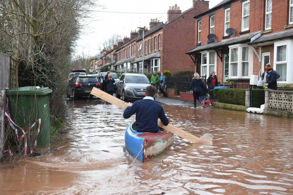 A man uses a plank of wood to paddle a kayak on floodwater near his house in Ross-on-Wye (AFP via Getty Images)