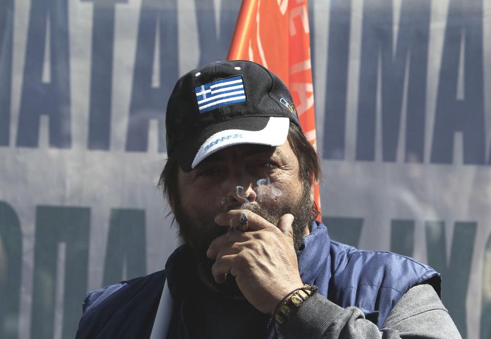 A protester with the Greek flag on his hat, smokes a cigar during a rally in Athens, on Wednesday, March 19, 2014. Greek civil servants, including hospital and teaching staff, have started a two-day strike against austerity measures imposed under the debt-mired country's international bailout commitments. (AP Photo/Thanassis Stavrakis)