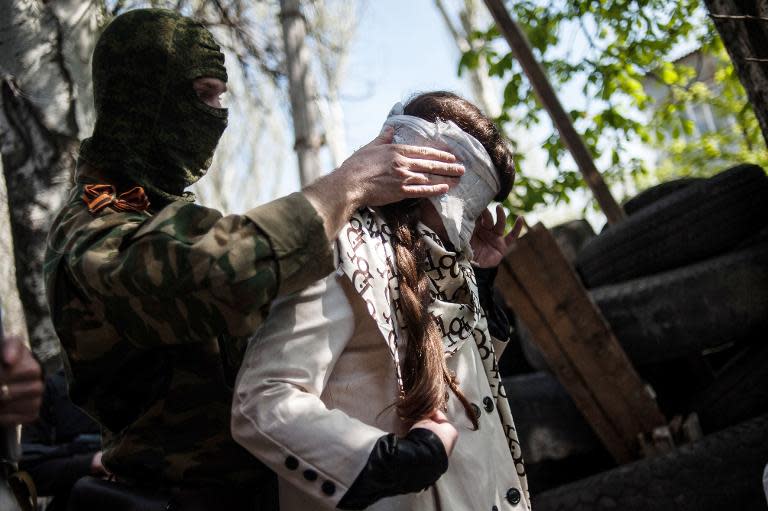 A pro-Russian separatist blindfolds Irma Krat, a Ukrainian journalist working for a pro-Kiev outlet, as she is detained by pro-Russian separatists in the eastern Ukrainian city of Slavyansk on April 21, 2014