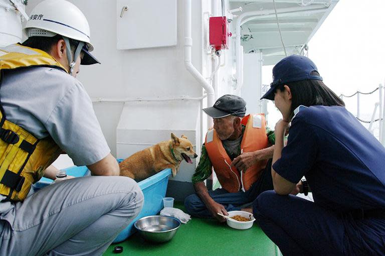 An elderly man and his dog are evacuated onboard a coast guard vessel from Kuchinoerabu island, on May 29, 2015