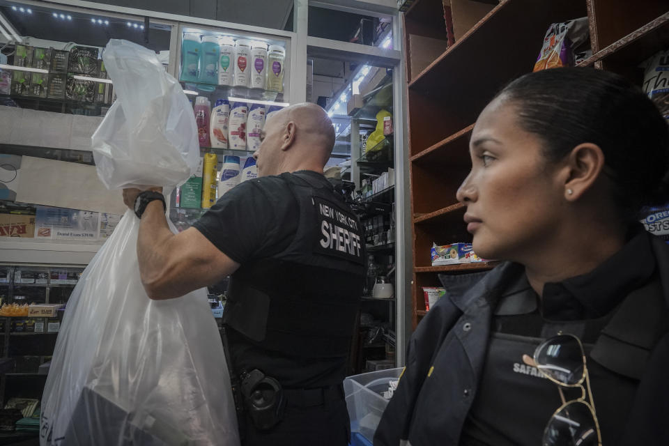 New York Sheriff's Chief of Detectives Philip Schaffroth, Jr., left, and Detective Veronica Robles, right, confiscate illegal vaping products, during a spot raid by New York Sheriff's Joint Compliance Task Force (SJCTF) of a tobacco store, Wednesday Sept. 27, 2023, in New York. Communities across the U.S. are confronting a new vaping problem: how to get rid of millions of disposable e-cigarettes that are considered hazardous waste. The devices contain nicotine, lithium and other materials that cannot be reused or recycled. (AP Photo/Bebeto Matthews)
