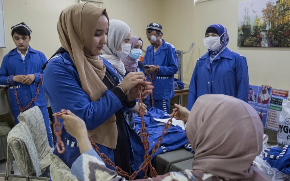 Uighur activists try on plastic chains and imitation prison uniforms ahead of a demonstration outside the Chinese embassy in Istanbul, Turkey - Sam Tarling for The Telegraph 