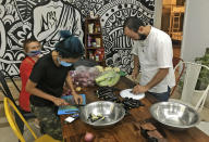 Stranded foreign tourists cut vegetables to make a meal at a hostel in New Delhi, India, Thursday, April 2, 2020. Dozens of tourists from Britain, Canada and Australia are finding themselves stranded in the Indian capital with their vacations abruptly ended by India’s three-week lockdown and stopping of international flights amid new coronavirus. (AP Photo/Shonal Ganguly)