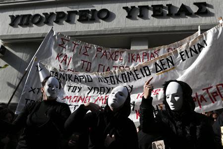 Protesters wearing masks perform during a protest organised by unions from the state health sector against the government's plans for cutbacks in medical staff and hospitals in front of the Health ministry in Athens November 29, 2013. REUTERS/John Kolesidis