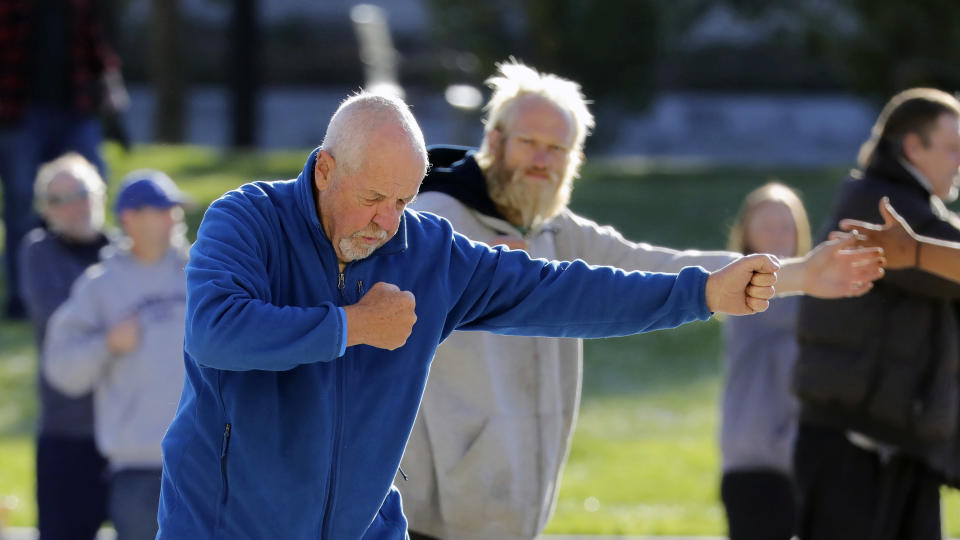 In this Oct. 7, 2019, photo, Bernie Hart, foreground, teaches tai chi in front of the Salt Lake Police headquarters, in Salt Lake City. The participants are homeless people who take part in a free tai chi program run by Bernie and his wife Marita, a retired couple who started the classes three years ago by knocking on tents and peering around grocery carts near the Salt Lake City Public Library to encourage people to join them. (AP Photo/Rick Bowmer)