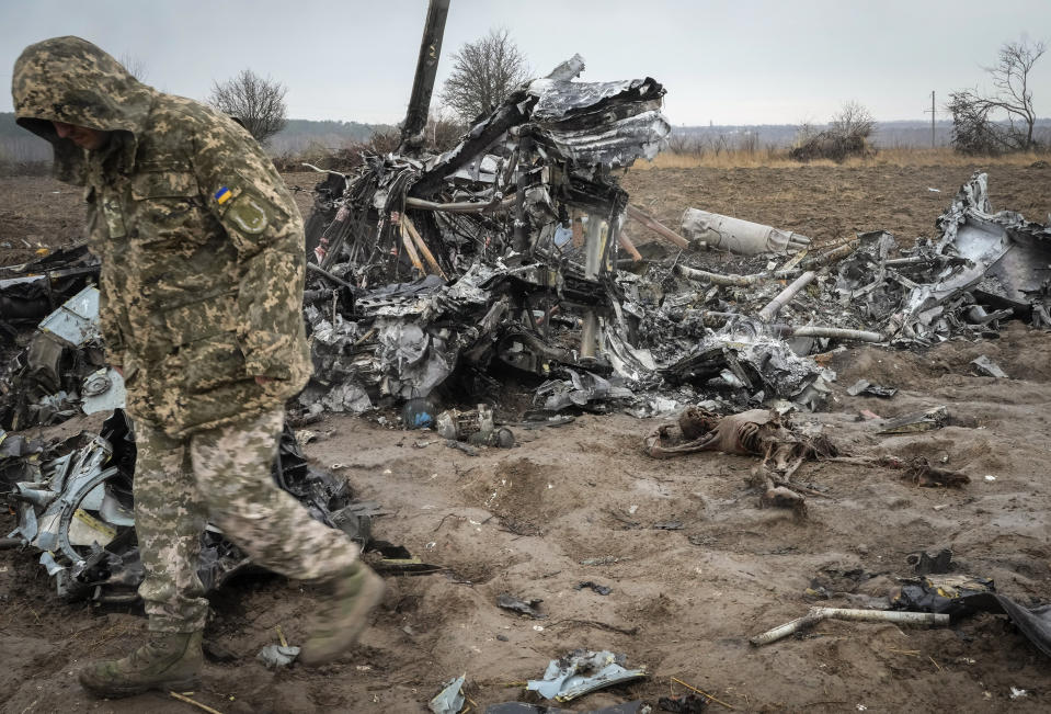 The remains of victims and the fragments of a Russian military helicopter lie on the ground near Makariv, close to Kyiv, Ukraine, Saturday, April 9, 2022. (AP Photo/Efrem Lukatsky)