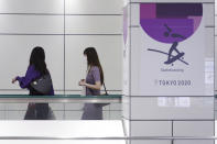 People wearing protective masks to help curb the spread of the coronavirus walk near a Tokyo 2020 Olympic Games advertisement Tuesday, June 22, 2021, in Tokyo. (AP Photo/Eugene Hoshiko)