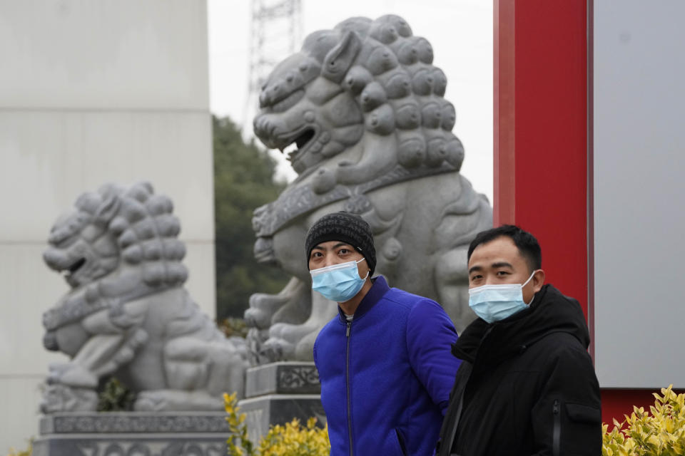 Chinese men wearing masks stand near stone lions across from the Wuhan Jinyintan Hospital where a team from the World Health Organization visited in Wuhan in central China's Hubei province on Saturday, Jan. 30, 2021. (AP Photo/Ng Han Guan)