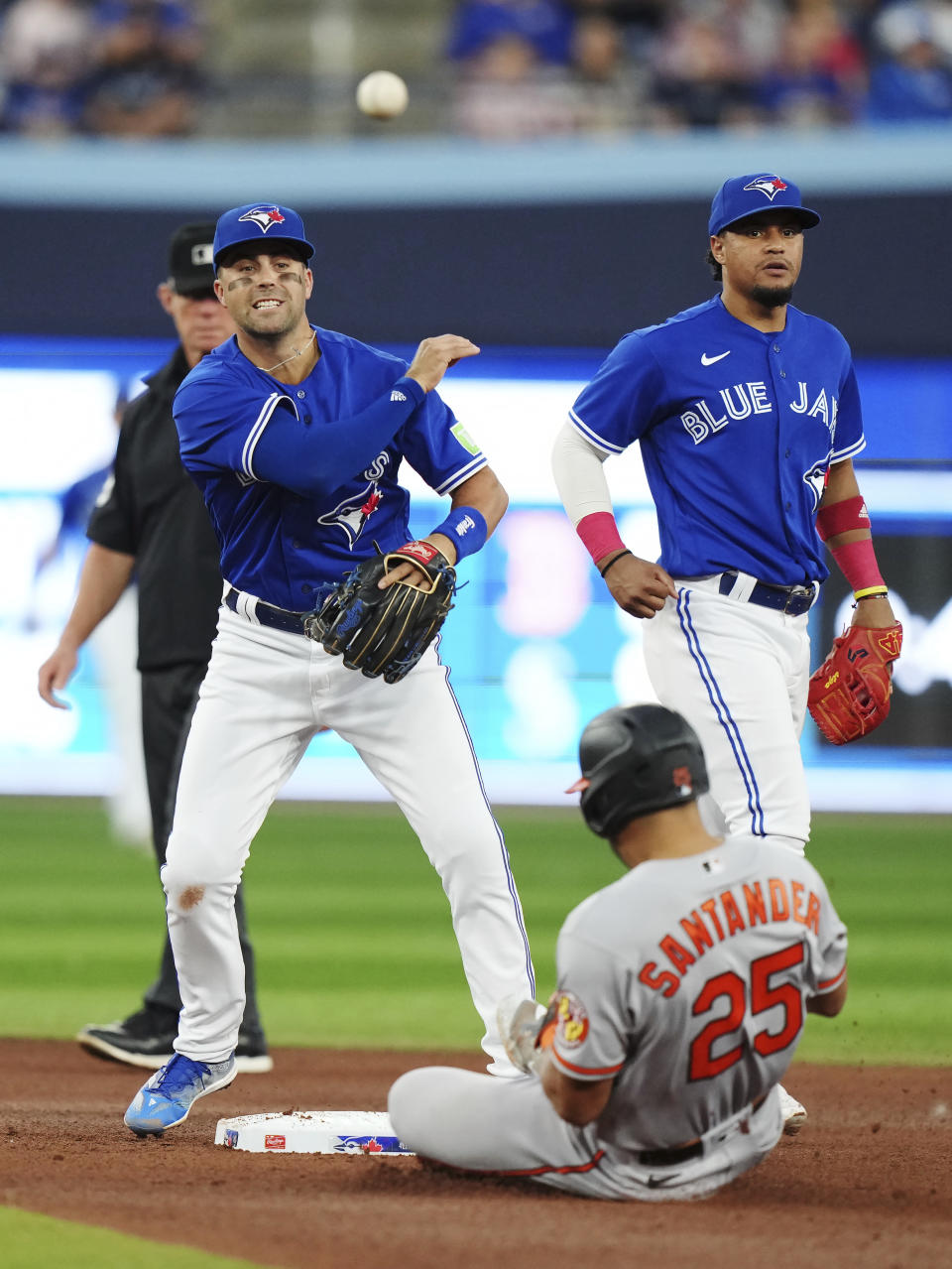 Toronto Blue Jays second baseman Whit Merrifield, left, forces out Baltimore Orioles' Anthony Santander (25) and throws to first base to complete the double play during the fifth inning of a baseball game in Toronto on Tuesday, Aug. 1, 2023. (Nathan Denette/The Canadian Press via AP)