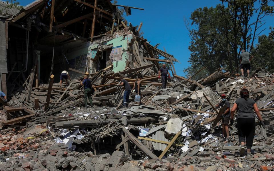 People remove debris of a building of the lyceum of railway transport destroyed by a missile strike, as Russia's attack on Ukraine continues, in the town of Liubotyn, in Kharkiv region, Ukraine June 20, 2022. - REUTERS/Vyacheslav Madiyevskyy