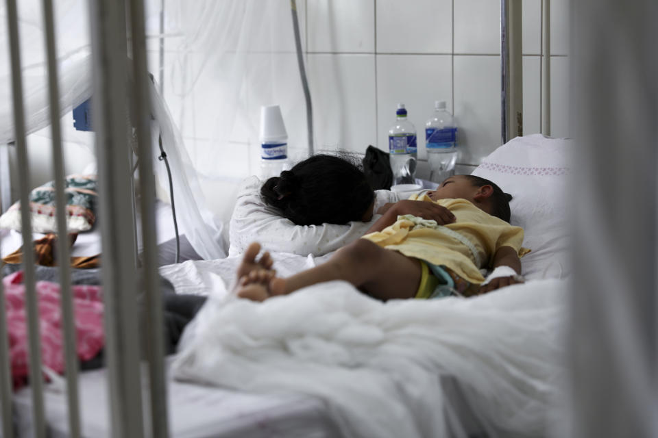 In this photo taken on Aug. 20, 2019, a patient receives treatment for dengue and is taken care of by a relative inside a room at the University School Hospital in Tegucigalpa, Honduras. In a ward usually reserved for juvenile burn victims, children lay listlessly under mosquito nets next to worried parents. (AP Photo/Eduardo Verdugo)